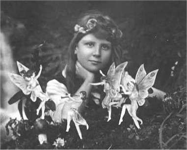 Girl posing behind group of paper fairies in 1917 photo