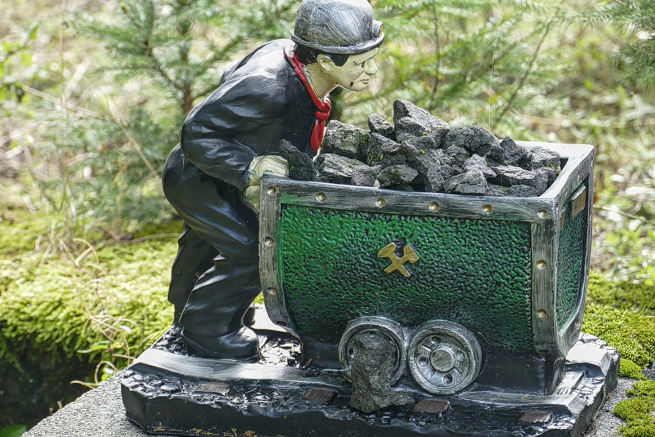 Photograph of a figurine of a miner pushing a cart of ore along steel tracks